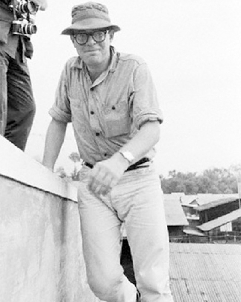 Black and white of photograph of American writer Michael Herr standing.