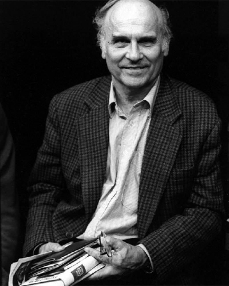 Black and white photograph of Ryszard Kapuściński holding a book.