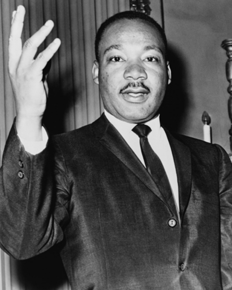 Black-and-white photograph of Martin Luther King Jr. with his right hand lifted