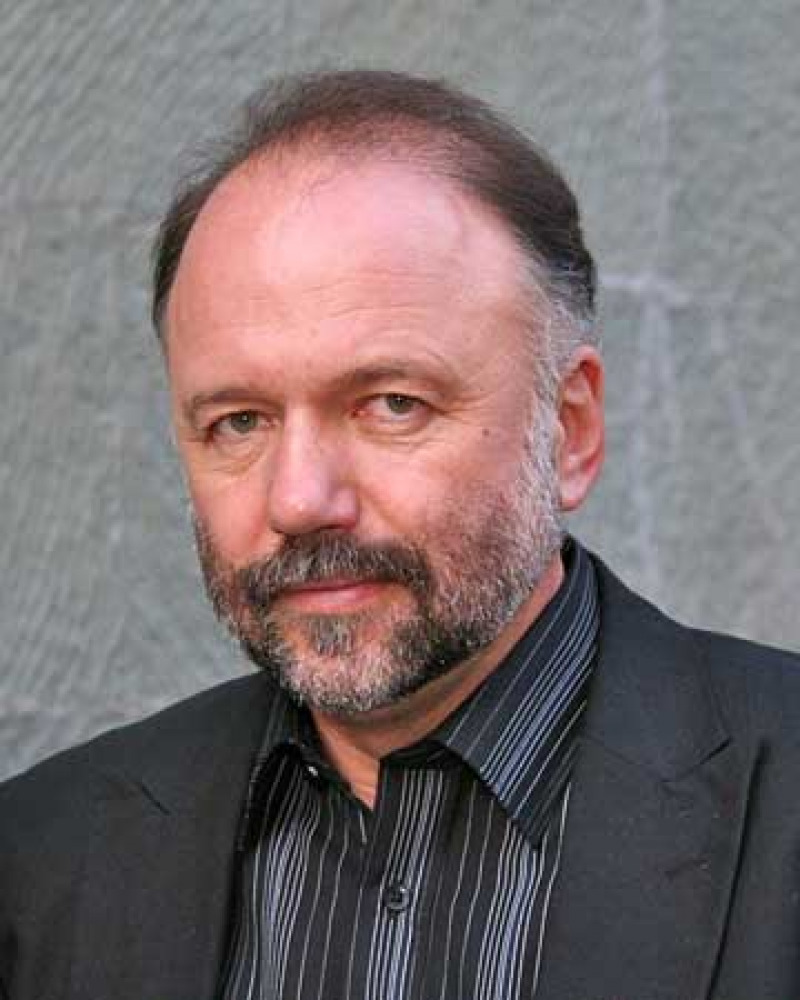 Man with a graying beard wearing a dark suit jacket