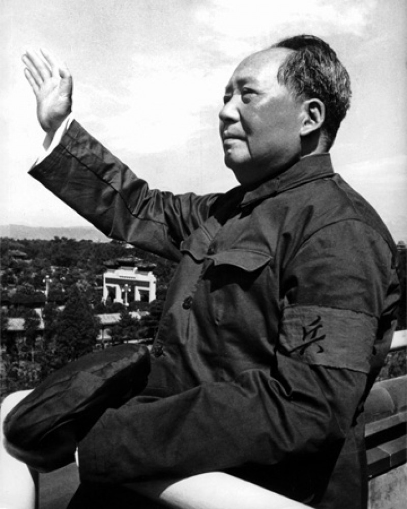 Black and white photograph of Mao Zedong with raised arm.