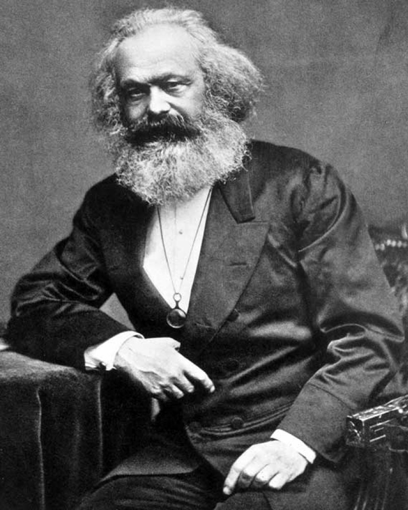 Seated man with a large white beard wearing a dark suit