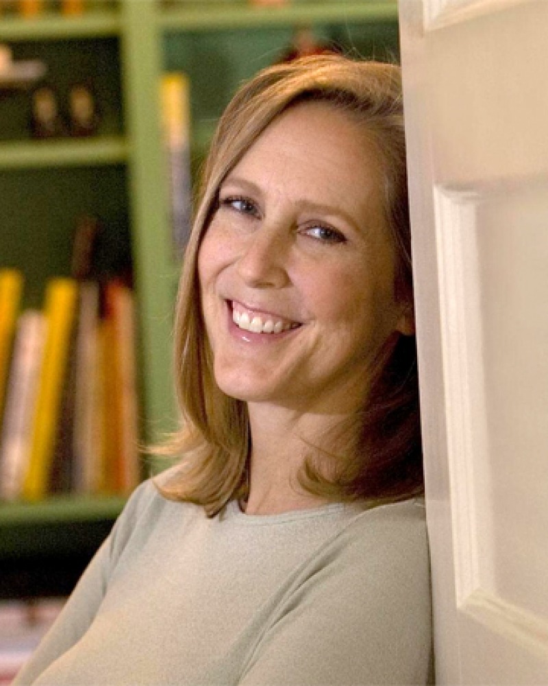 Color photograph of American writer Mary Roach leaning on door.