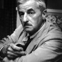Photograph of William Faulkner sitting in a chair.