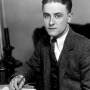 Black and white photograph of a young F. Scott Fitzgerald sitting at a desk.