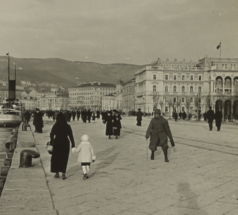 Sepia photograph of the Trieste waterfront with people walking, c. 1914.