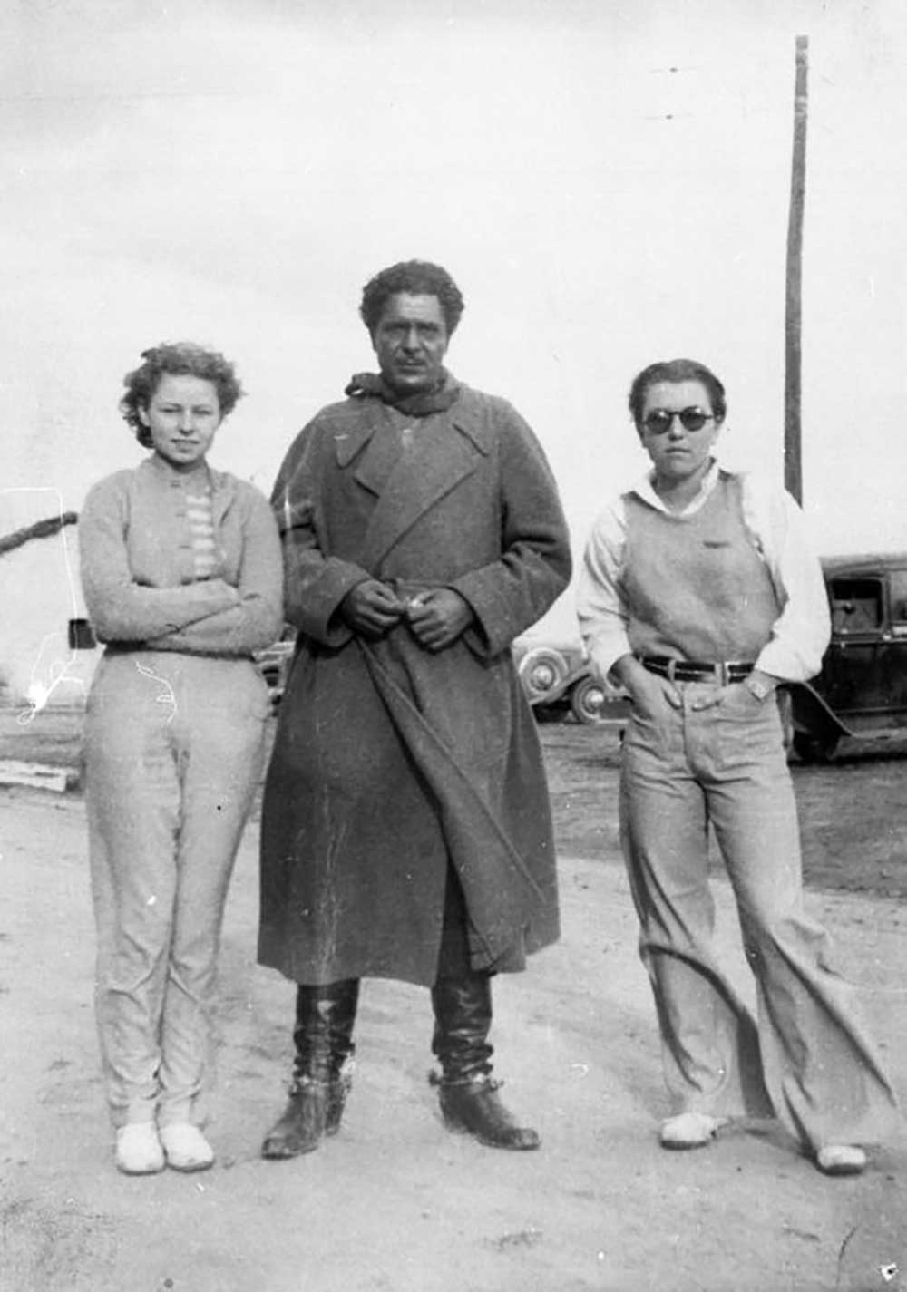 Black-and-white photograph of a man in brownface between two young women.