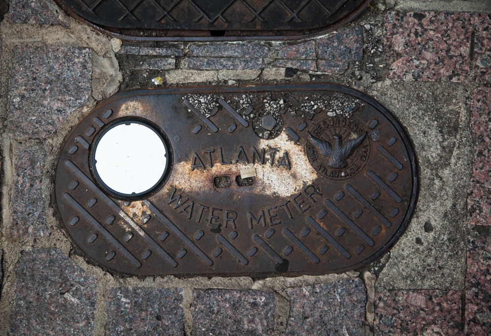 An Atlanta water meter cover, stamped with the city seal depicting a phoenix rising from its own ashes. Photo by Artem Nazarov.