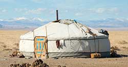 Round white tent with a hole at the top and a wood door